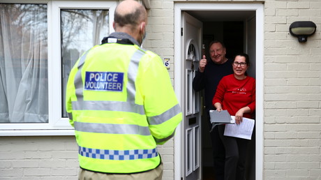 Un volontaire de la police propose à des résidents de se faire tester, au Royaume-Uni.