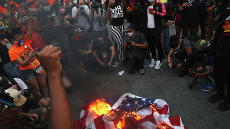 Des manifestants rassemblés à l'appel de Black Lives Matter brûlent un drapeau américain à Washington DC, le 4 juillet 2020.