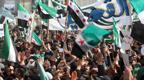 Des manifestants agitent des drapeaux de l'opposition syrienne lors d'une manifestation dans la ville syrienne d'Idlib, tenue par les rebelles, le 15 mars 2021.