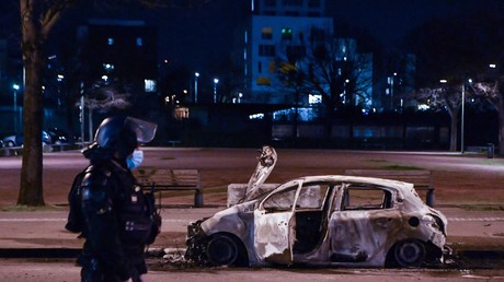 10 mars 2021 à Bron, en banlieue de Lyon, un membre des forces de sécurité intérieure devant un véhicule carbonisé, après des violences urbaines qui ont duré trois nuits (image d'illustration).