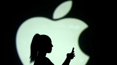 Une silhouette féminine tient son smartphone devant un logo d'Apple le 28 mars 2018 (image d'illustration).
