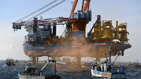 Des bateaux de pêche encerclent le navire plateforme de forage Aeolus dans la baie de Saint-Brieuc, dans l'ouest de la France le 7 mai 2021, pour protester contre le projet de construction de 62 éoliennes au large de la baie.