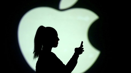 Une utilisatrice de smartphone devant le logo d'Apple, le 28 mars 2018 (image d'illustration)