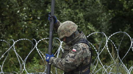 Un soldat polonais réajuste une clôture en fil de fer barbelé à la frontière avec la Biélorussie, le 26 août 2021.
