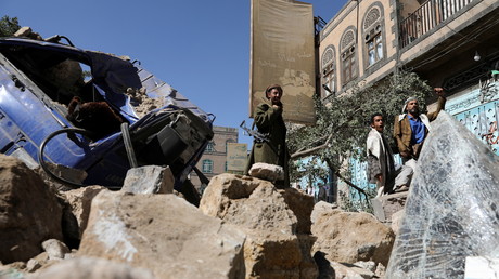 Un soldat et des passants se tiennent à côté d'un véhicule détruit par une frappe aérienne menée par les Saoudiens à Sanaa, au Yémen, le 24 décembre 2021.