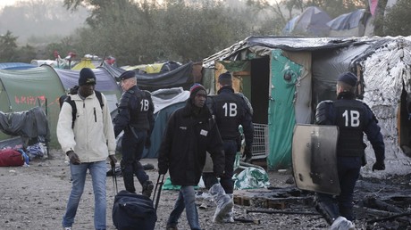 Des migrants passent devant des policiers français alors qu'ils quittent un camp près de Calais, le 27 octobre 2016 (image d'illustration).