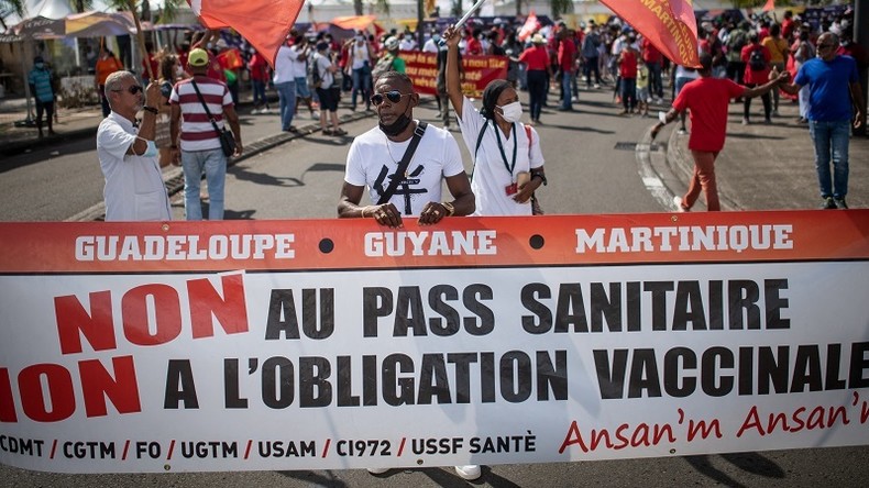 Des manifestants portent une banderole hostile au pass sanitaire et à la vaccination obligatoire à Fort-de-France