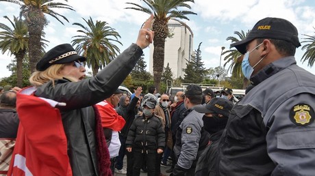 Une manifestante tunisienne fait face à un policier lors de manifestations organisées à Tunis le 14 janvier 2022.