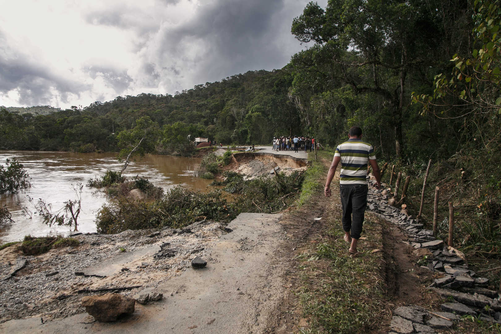 Un homme marche le long de la RN25 partiellement effondrée à Ranomafana le 7 février 2022 suite au passage du cyclone Batsirai.