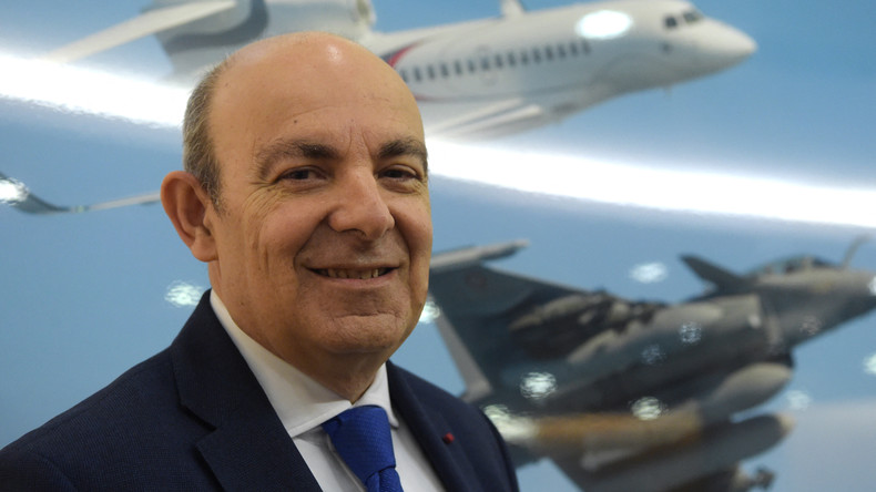 Eric Trappier devant une image représentant un Falcon et un Rafale