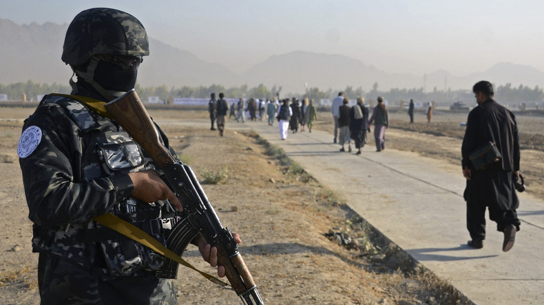 Un combattant taliban monte la garde alors que des fidèles musulmans arrivent pour effectuer les prières de l'Aïd al-Fitr