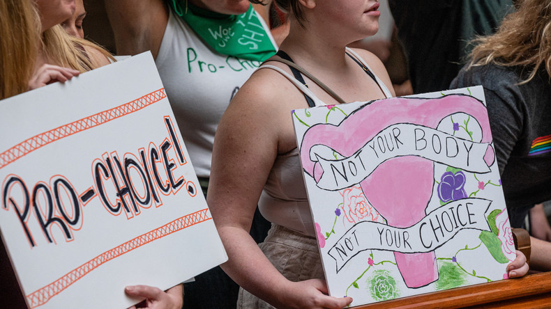 Une militante pour le droit à l'avortement tient une pancarte à côté d'une militante anti-avortement dans le bâtiment du Capitole de l'Indiana, le 25 juillet 2022