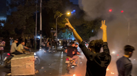 Manifestant levant les bras et faisant le signe de la victoire lors d'une manifestation pour Mahsa Amini, une femme décédée après avoir été arrêtée par la 