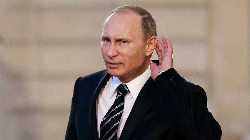 Владимир Путин надава ухо, за да чуе въпрос на тръгване от среща на върха, посветена на украинската криза в Елисейския дворец в Париж.
