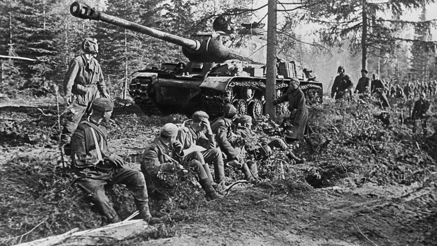 A heavy tank IS-2 and soldiers on a forest road.