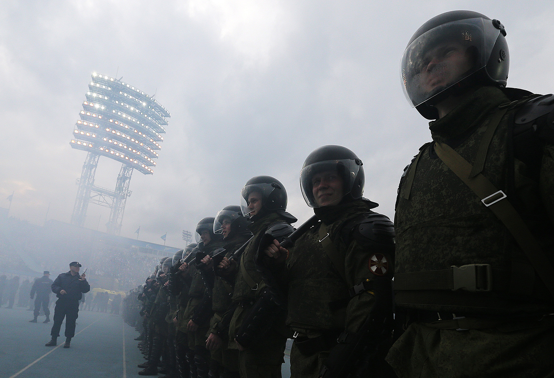 Petugas kepolisian saat penggemar sepak bola Rusia menyalakan api di Liga Primer Rusia 2014/2015.
