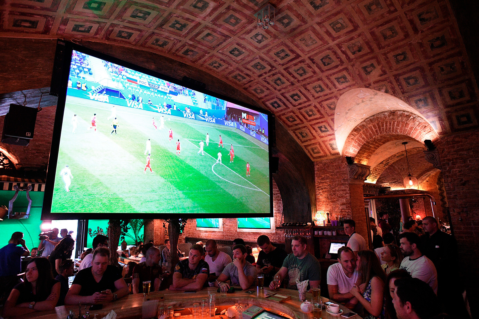 Fans watch the opening ceremony of the 2017 FIFA Confederations Cup at Liga Pap pub in Moscow.