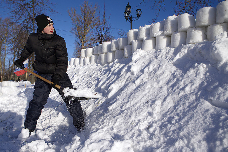 Habitante local fortifica a parede de uma fortaleza de neve em Ribinsk.