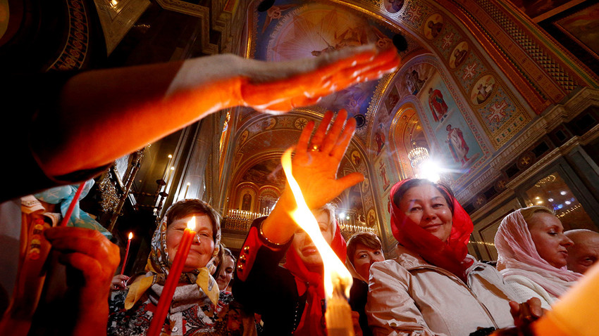 Para jemaat berusaha menyentuh lilin Api Suci selama ibadah Paskah Ortodoks di Katedral Kristus Sang Penyelamat di Moskow, Rusia.