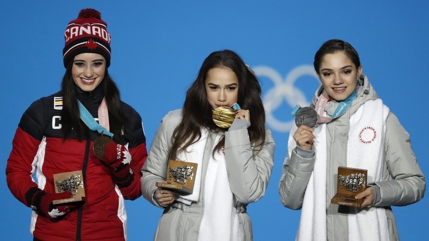Peraih medali emas Alina Zagitova (tengah), peraih medali perak Evgenia Medvedeva (kanan), dan peraih medali perunggu Kaetlyn Osmond dari Kanada (kiri) di atas podium.