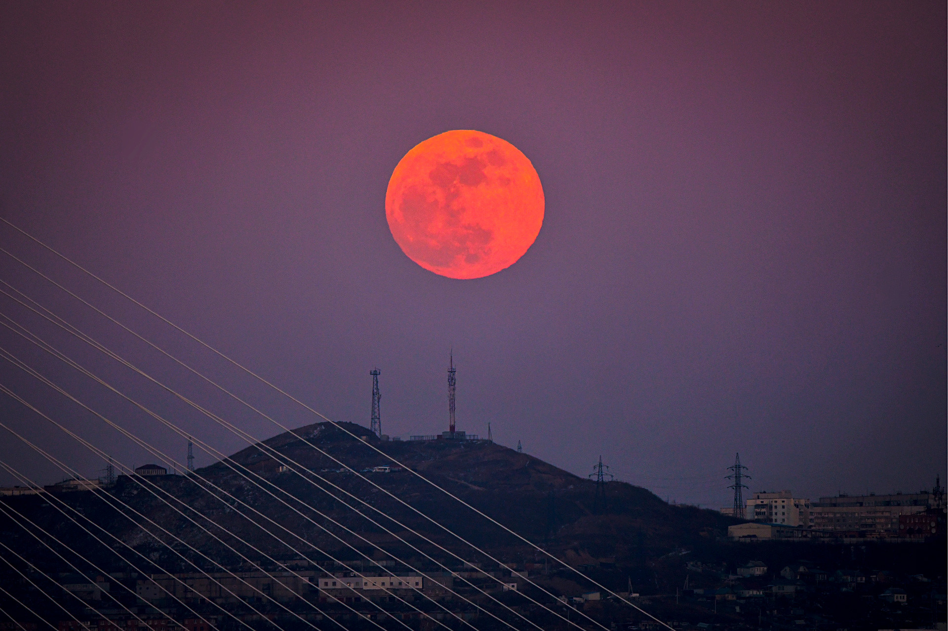 The red full moon rises over hills in the city of Vladivostok in Russia's Far East as a Blue Moon, supermoon and total lunar eclipse occur at the same time. 
