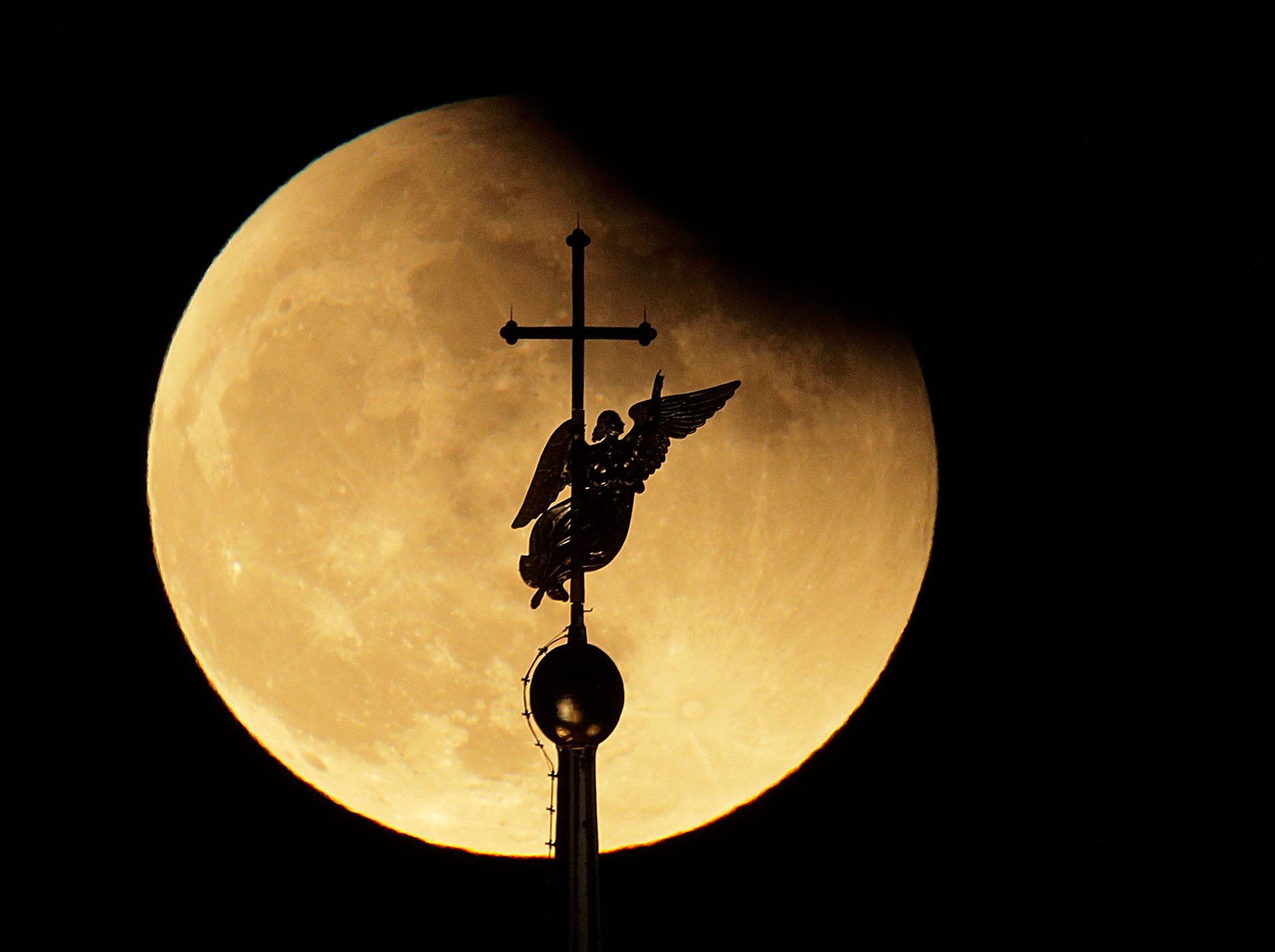Градскиот ветроказ во форма на ангел на врвот на црквата „Св. Петар и Павле“ во Санкт Петербург на фон на месечината.

 
