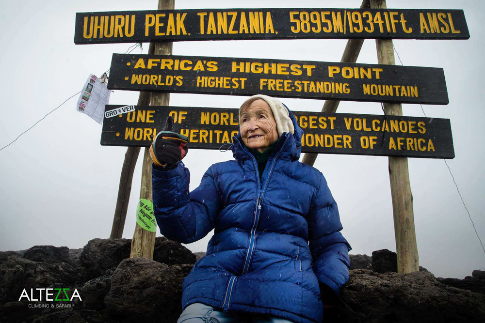 Angela Vorobiova, que acaba de estabelecer um novo recorde mundial, próxima às placas de Uhuru Peak (o ponto mais alto do Kilimanjaro). 