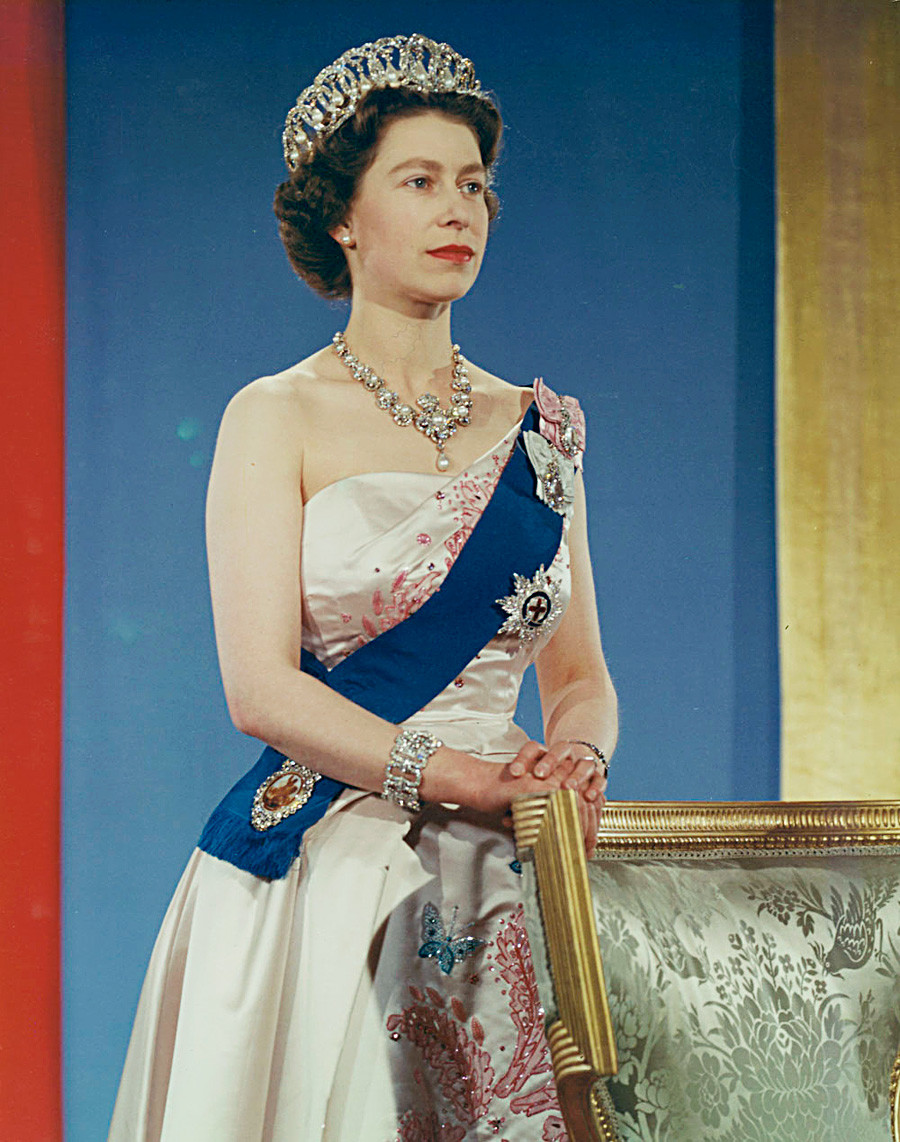 Ratu Elizabeth II mengenakan mahkota, gaun biru, dan selempang  pink.