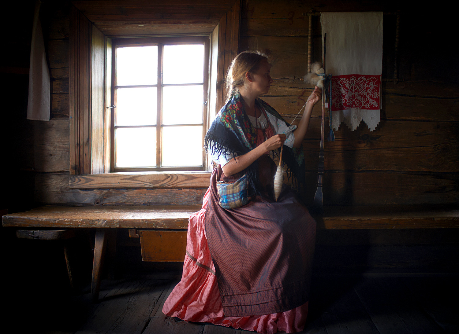 A woman in national clothes spinning yarn in the Kizhi State Historical-Architectural and Ethnographic Museum Reserve.