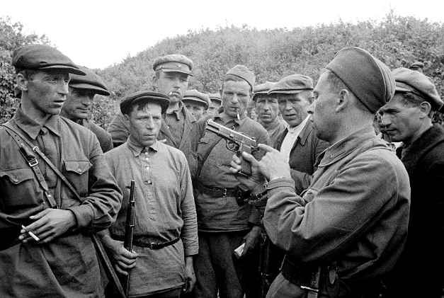 Partizanski poveljnik uči svoje vojake uporabljati orožje.