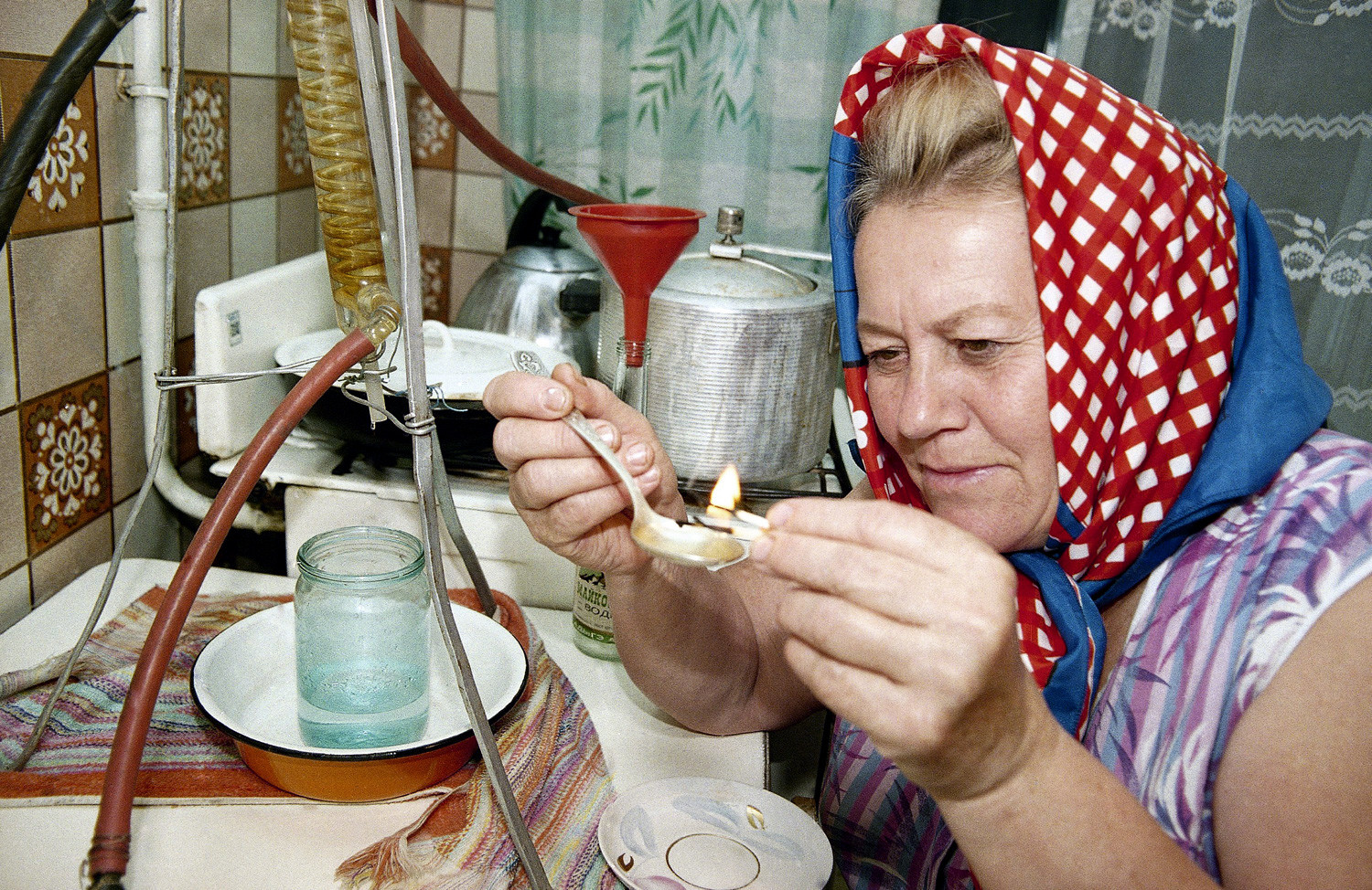 A woman in the southern Russian city of Maikop lights with a match a spoonful of the moonshine she made, to check its quality