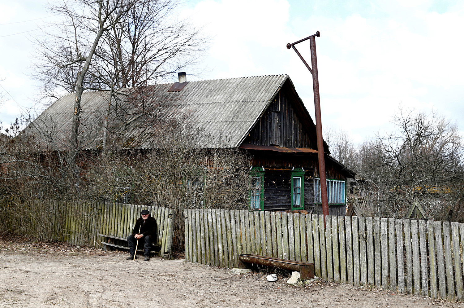 Ivan Shamyanok, 90, sits in front of his house in the village of Tulgovichi, near the exclusion zone. He is not eager to leave his land.