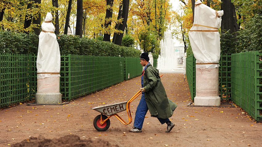 Municipal workers cleaning up fallen leaves in the Summer Garden in St. Petersburg