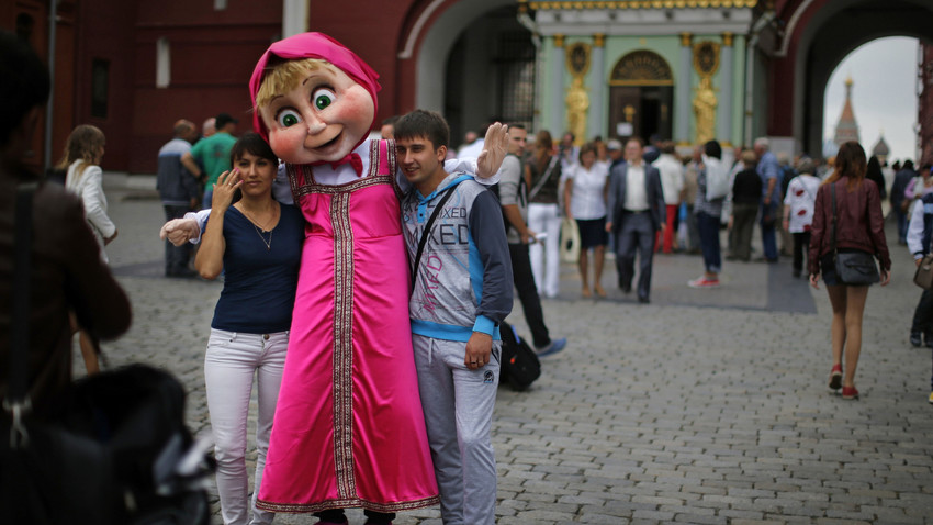 Dua orang turis berfoto bersama tokoh serial animasi Rusia, Masha, di Lapangan Merah, Moskow.