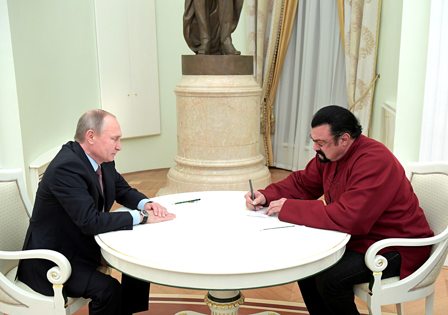 Steven Seagal signs a Russian passport received from Russia's President Vladimir Putin during a meeting at the Kremlin in Moscow, November 25, 2016