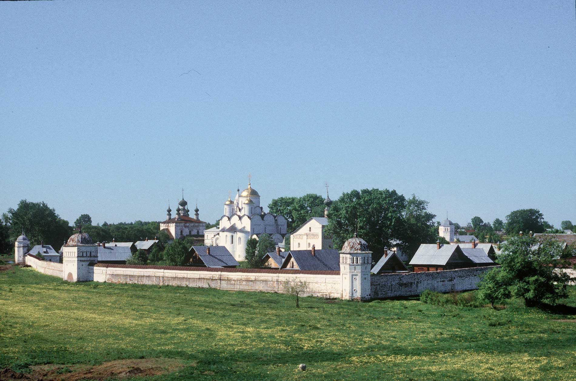 Intercession Convent, east wall and gate, northeast view from Savior-Evfimy Monastery. From left: Church of Sts. Peter&Paul (beyond convent), ​Intercession Cathedral with restored domes, refectory Church of St. Anne. May 23, 1996.