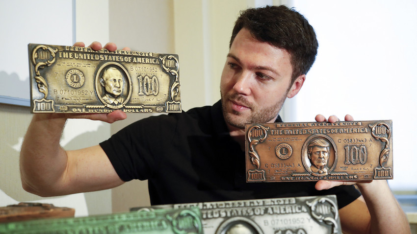 Former hacker Sergey Pavlovich holds mock money printing plates with Russian President Putin, left, and U.S. President Donald Trump faces in place of Benjamin Franklin during an interview with the Associated Press in Moscow, Russia, Wednesday, Aug. 9, 2017