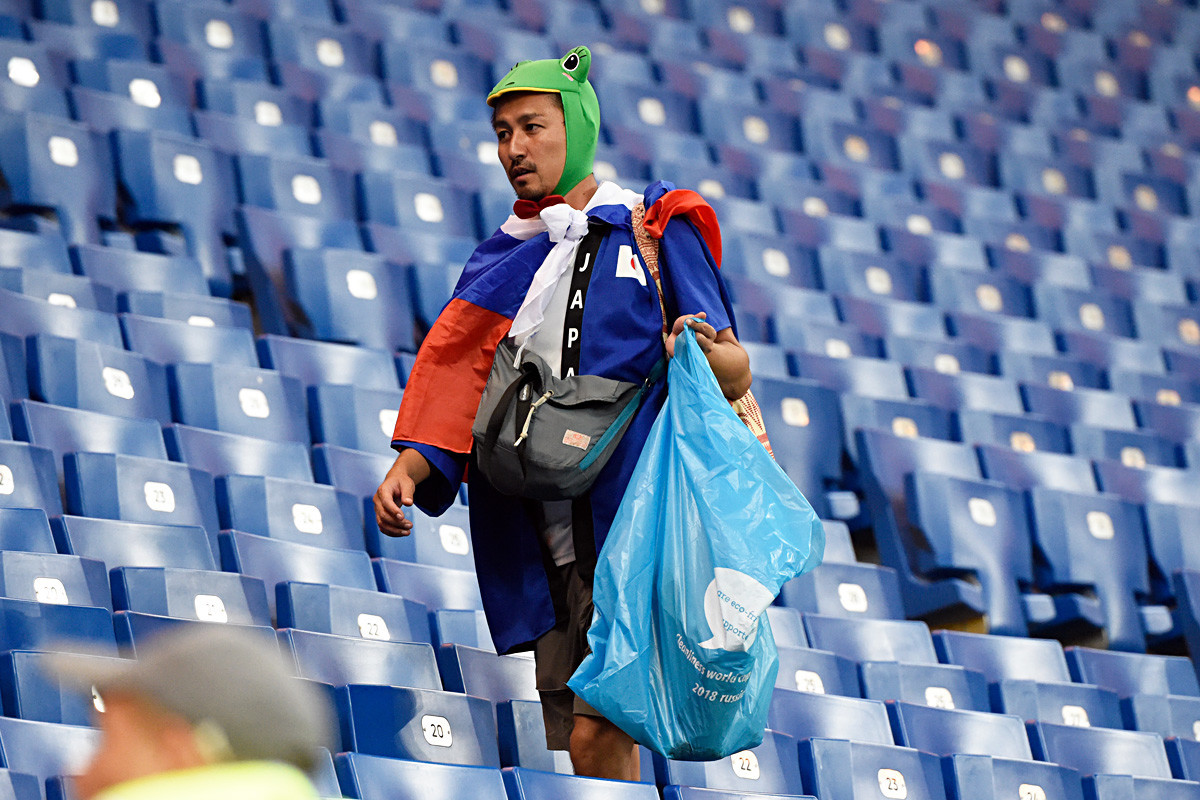 Seorang suporter Jepang mengumpulkan sampah setelah pertandingan sepak bola Piala Dunia 2018 antara Belgia dan Jepang di Rostov Arena di Rostov-On-Don, pada 2 Juli 2018.