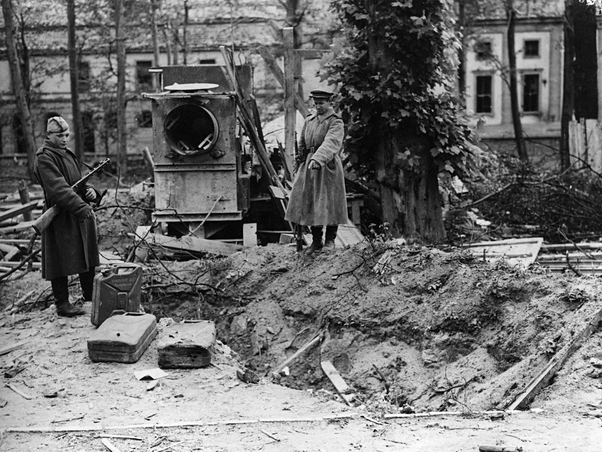 Двама руски войници сочат към това, което се твърди, че е гробът на Хитлер зад канцеларията на Райха в Берлин
