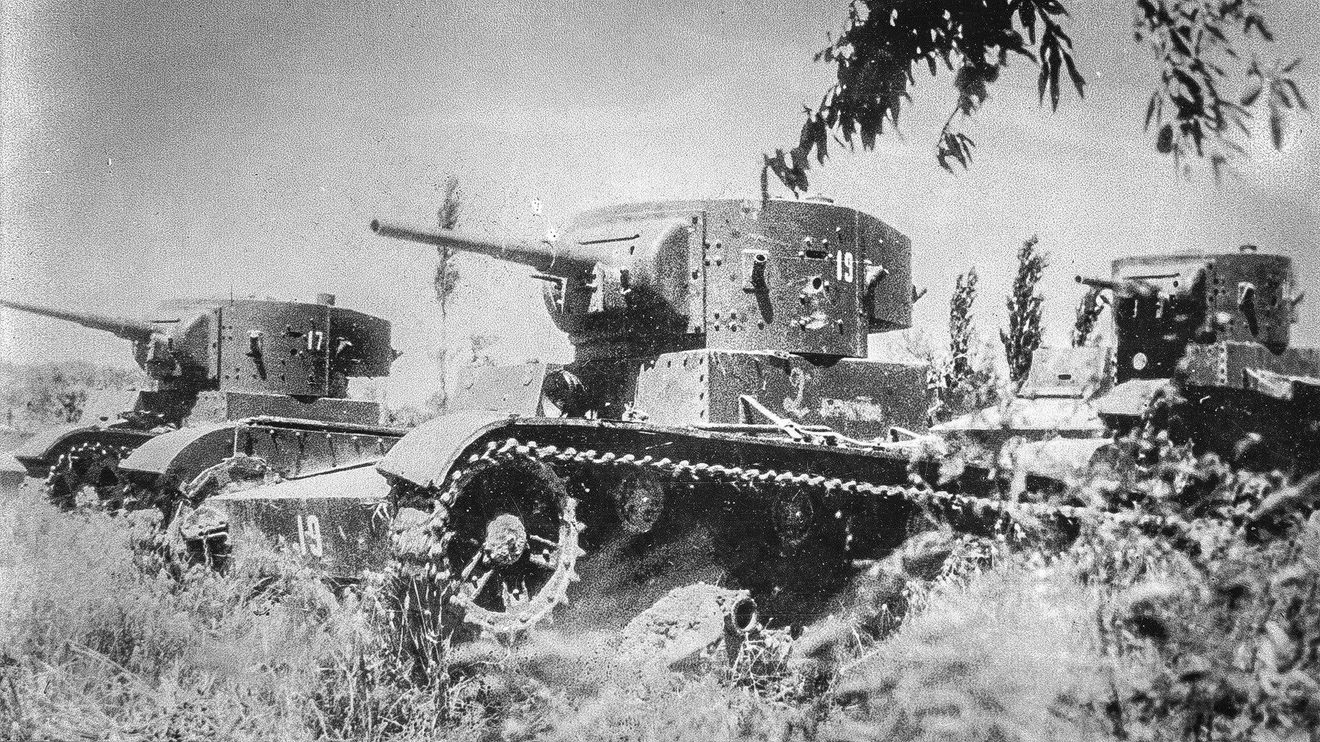 Three T-26 light tanks made in the Soviet Union travel through a field during a battle in Spain, during the Spanish Civil War.