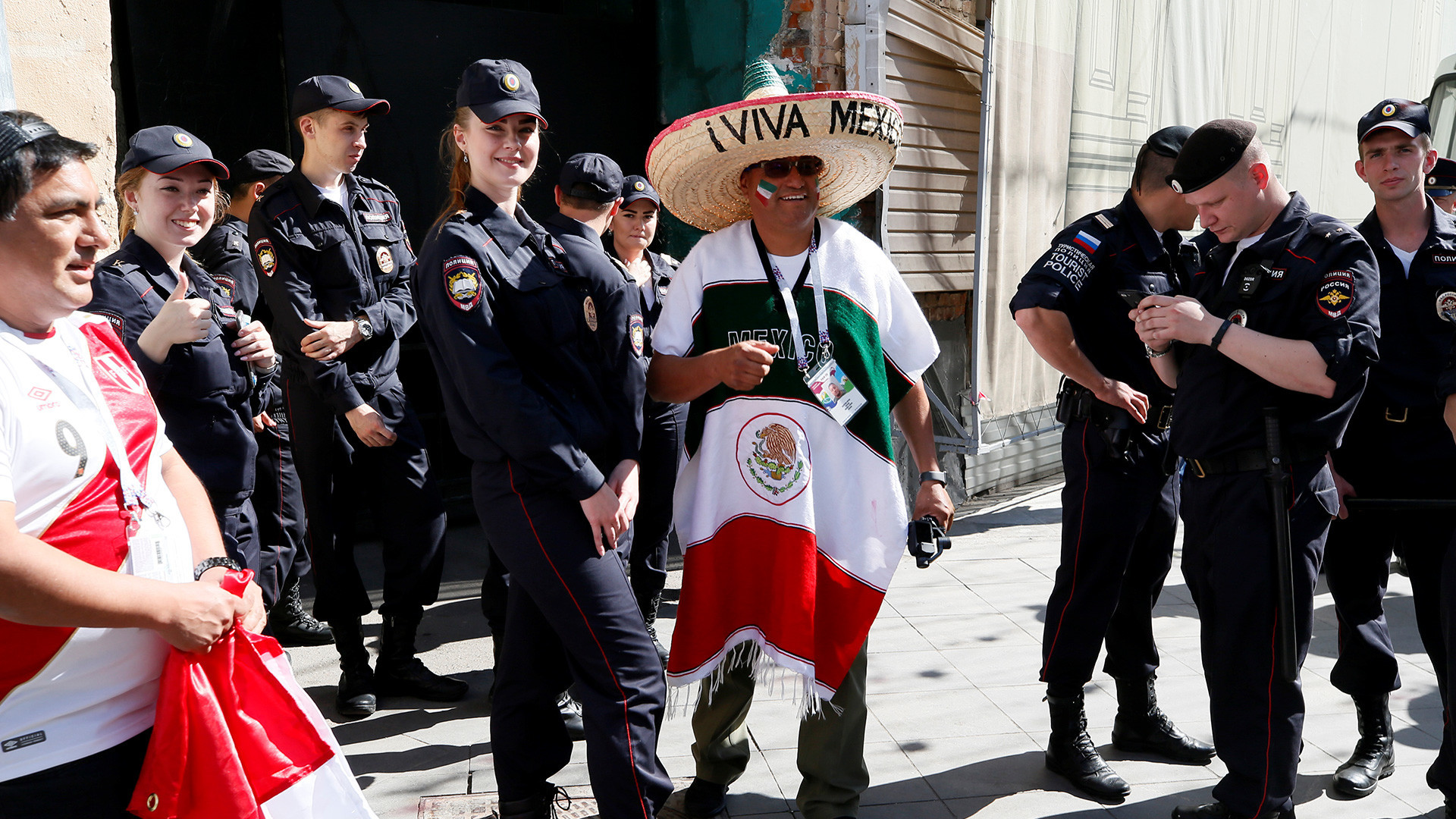 Pendukung tim nasional Meksiko dan Peru dengan polisi Rusia di Moskow, Rusia, 15 Juni 2018.