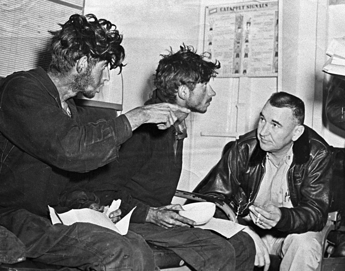 The emaciated Filipp Poplavsky, left, and Askhat Ziganshin, center, retell their plight to an American sailor after rescue on board the U.S. 