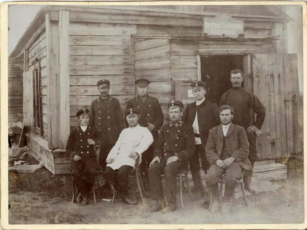 Carteros posan delante de una oficina de correos, década de 1900.