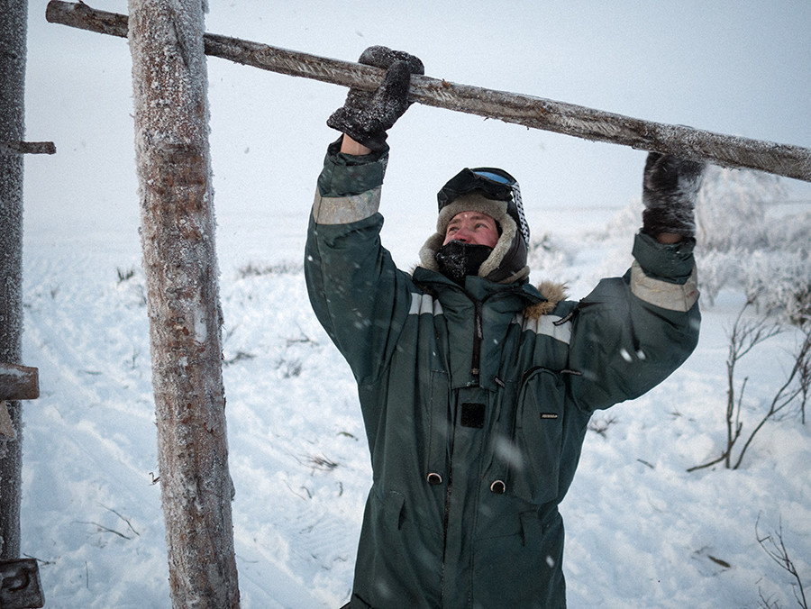 Andrey menutup palang setelah rusa kutub digiring dari tundra ke paddock. Ia kadang menghabiskan beberapa minggu atau bulan sendirian di tundra, mengurus kawanan rusa dan memperbaiki instalasi kayu.
