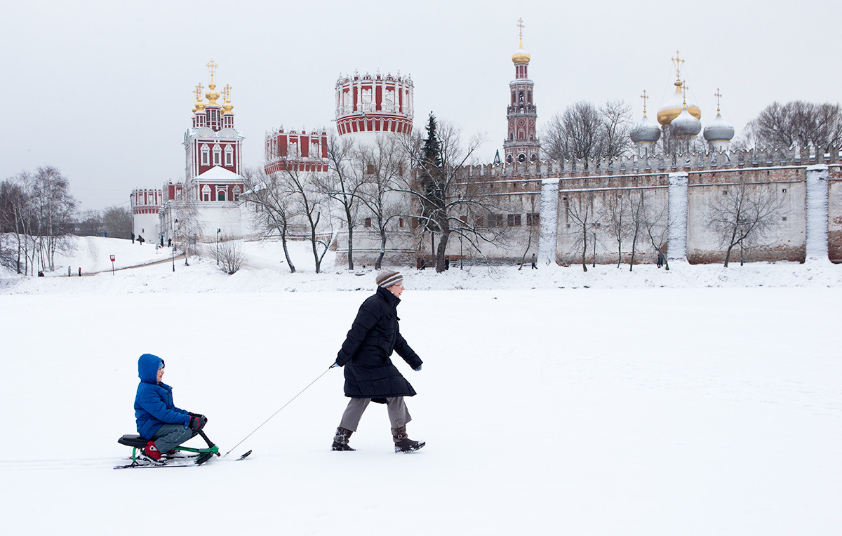Woman pulls a sled with a child on frozen pond in Moscow, Russia