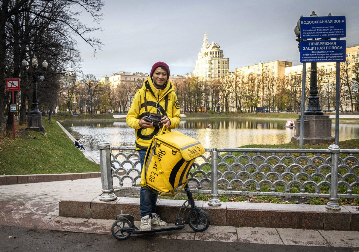 Sayid from Yandex Food delivery service poses with his smartphone in downtown Moscow on November 6, 2018