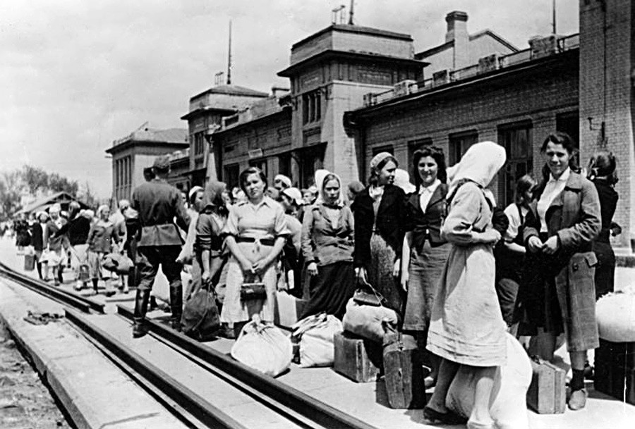 Момичета и жени се събират на гарата за транспортиране до Германия.