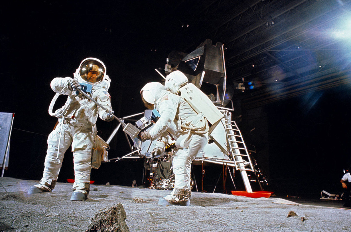 アポロ11号の月面着陸ミッションの二人のメンバーが月で使用する設備の配置や使用のシミュレーションをしている。1969年4月22日に行なわれた訓練の時。宇宙飛行士バズ・オルドリン（左）がスクープでサンプルを取っている。ニール・アームストロングがサンプルを受け取るためにバッグを持っている。後には月着陸船の模型がある。