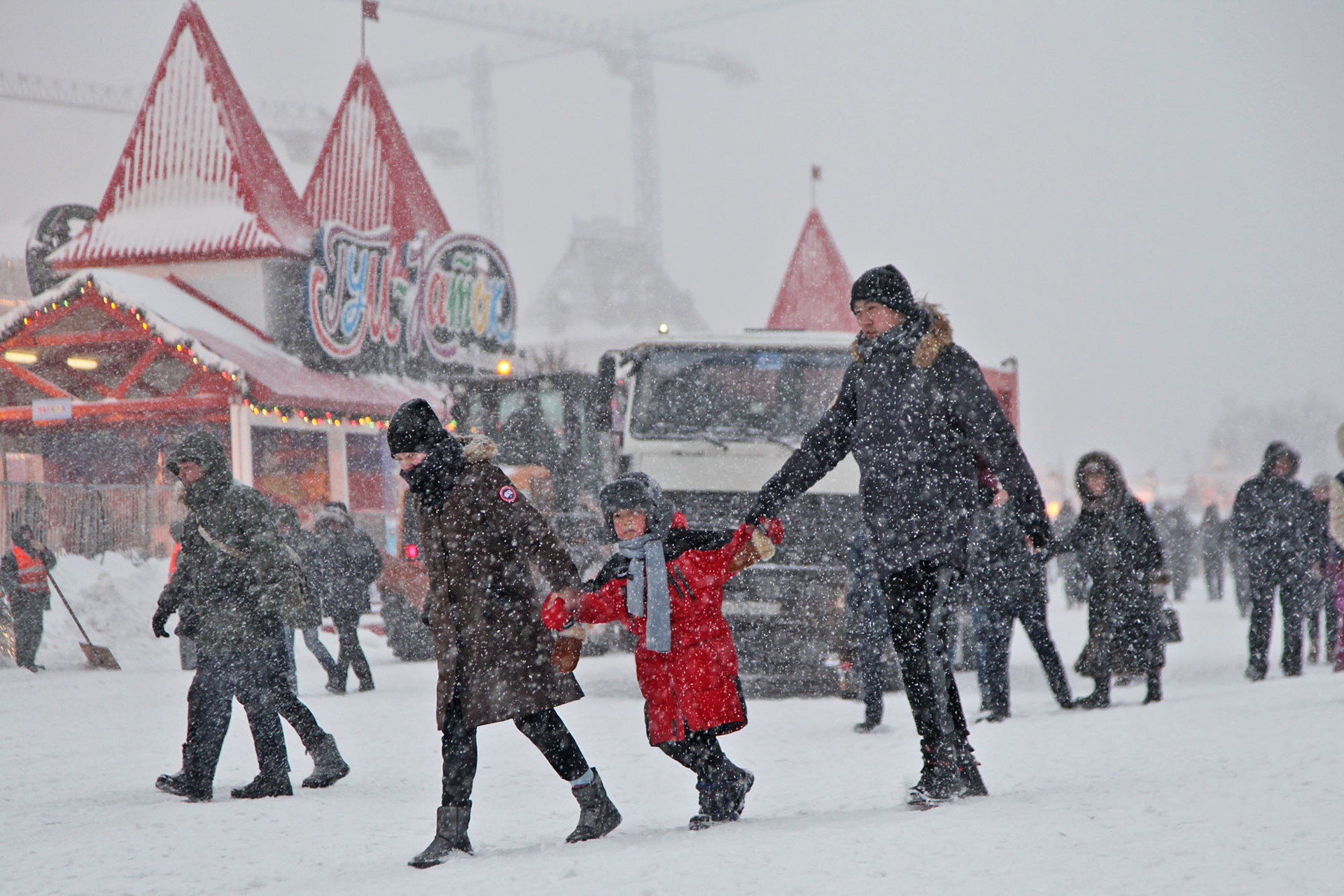 Pasangan suami istri mengandeng anak mereka saat badai salju di Lapangan Merah, Moskow, Rusia, Sabtu (26/1).    