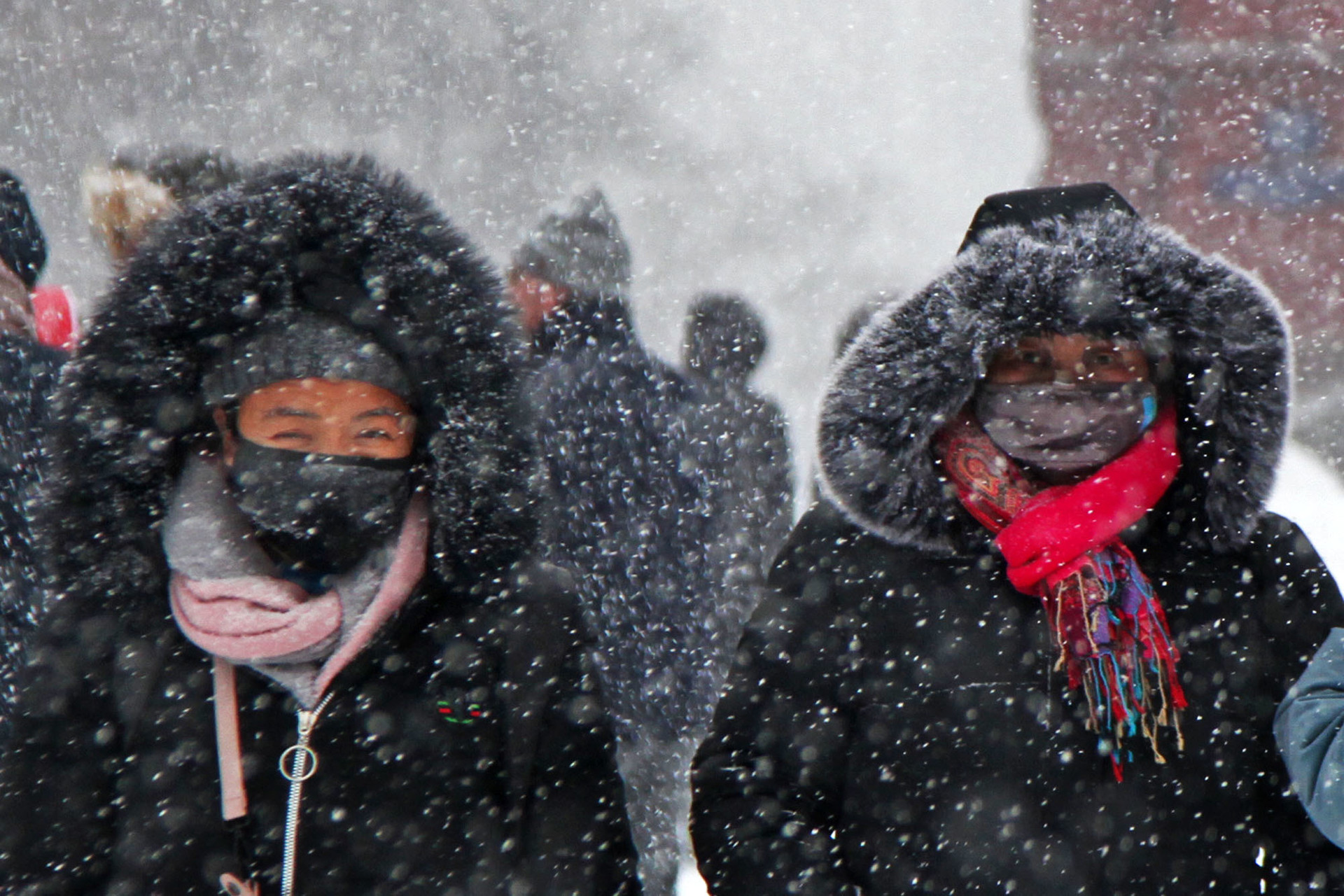 Pengunjung menutupi wajah saat badai salju di Lapangan Merah, Moskow, Rusia, Sabtu (26/1).    